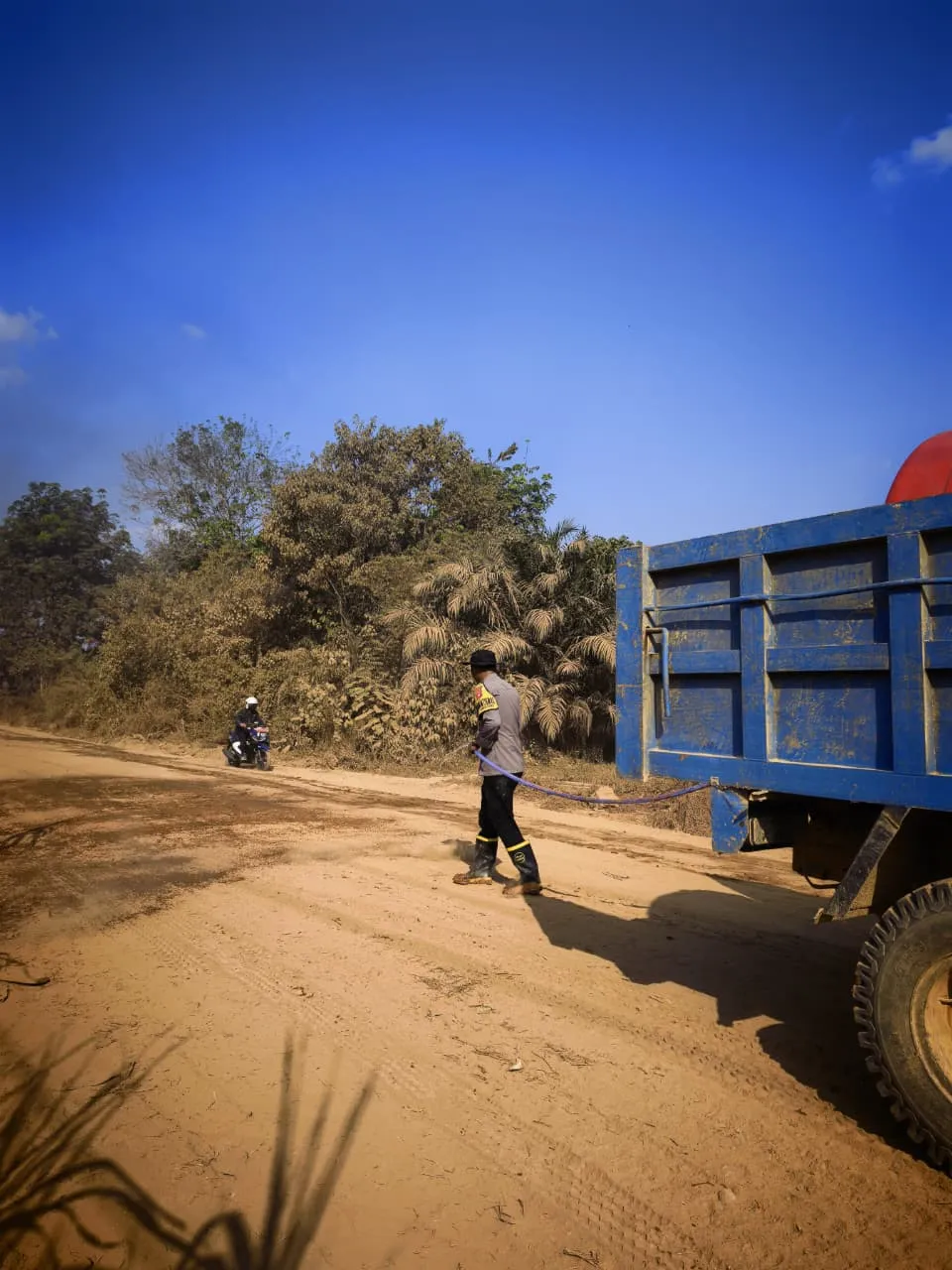 Peduli Kenyamanan Warga, Dua Personel Polsek Nanga Tayap Turun Langsung Siram Jalan Berdebu
